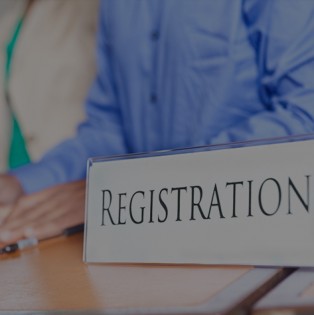Man sits at desk with sign that says "Registration"