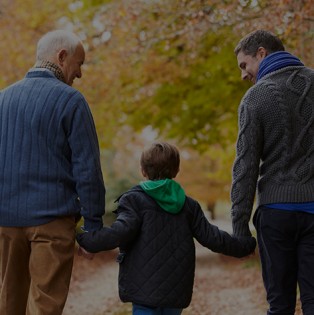 Father, son and grandson walk on a path in a forest.